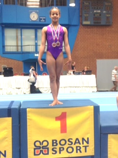Ella on top of the podium wearing her two Gold Medals