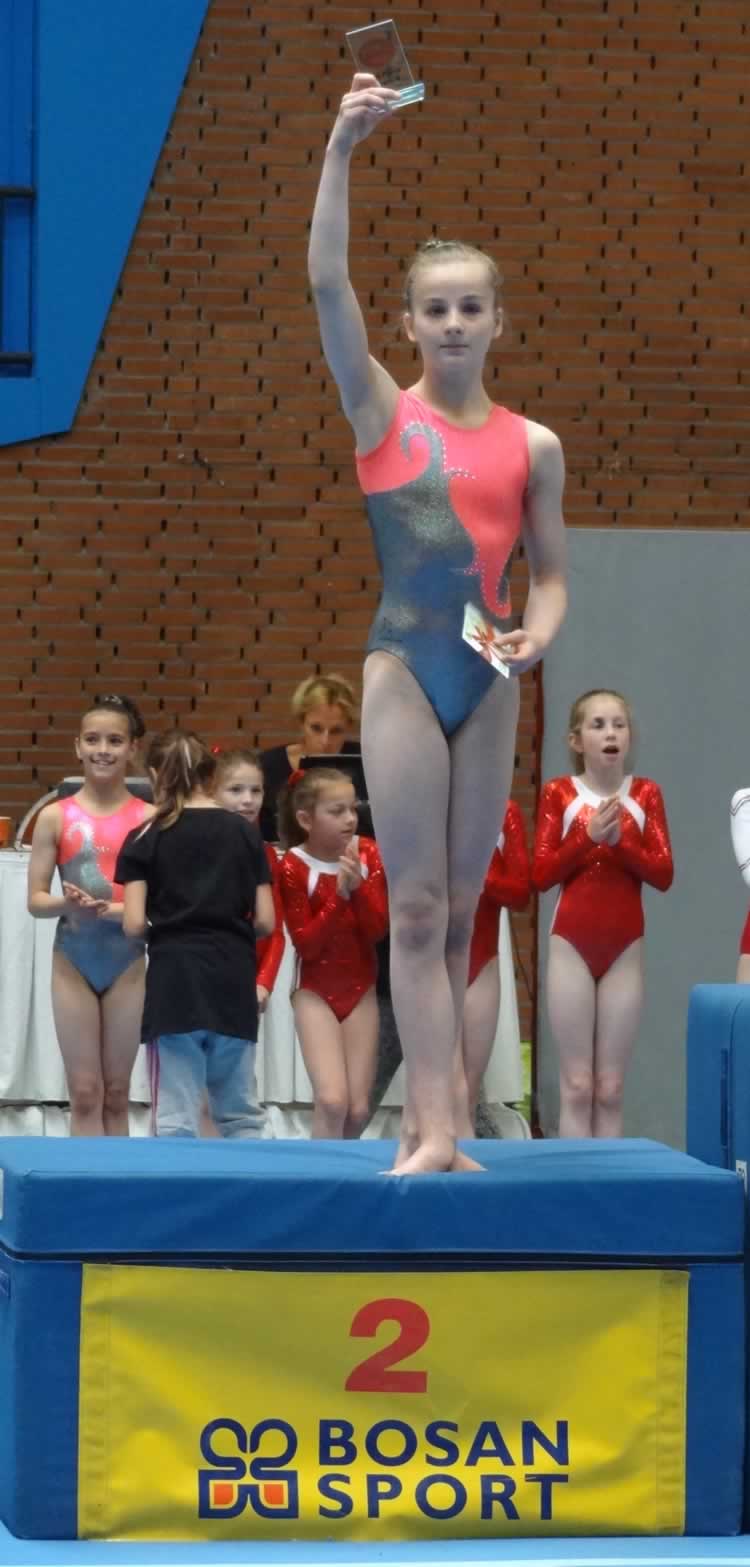 Isabel in second place on the podium holding her trophy aloft